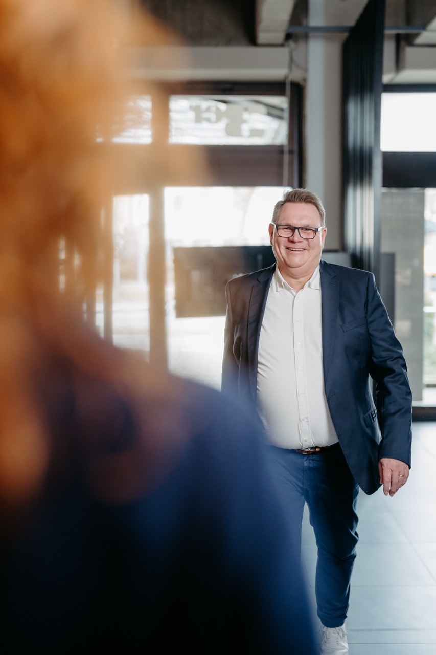 Alwin Justen begrüßt eine Kundin im Eingangsbereich