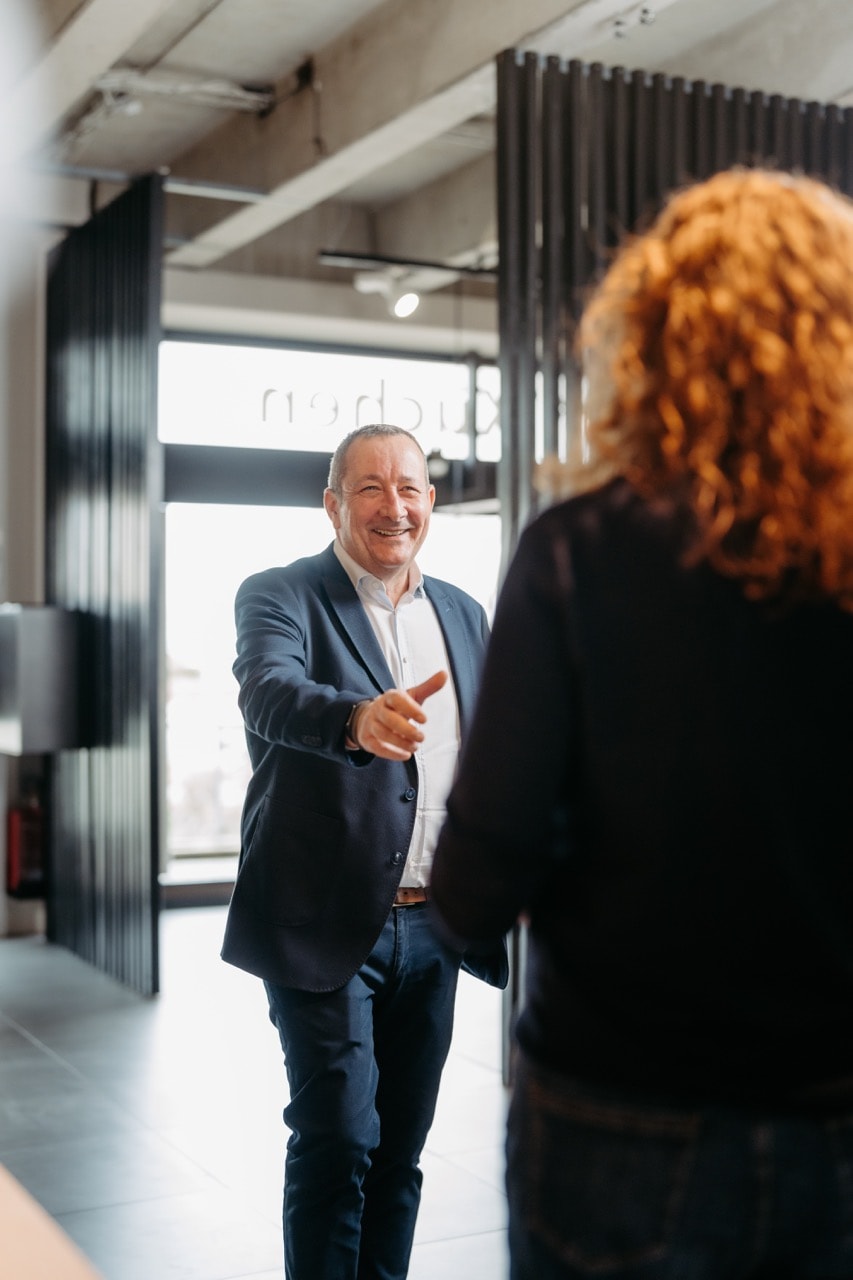 Stefan Tiemann begrüßt eine Kundin im Showroom