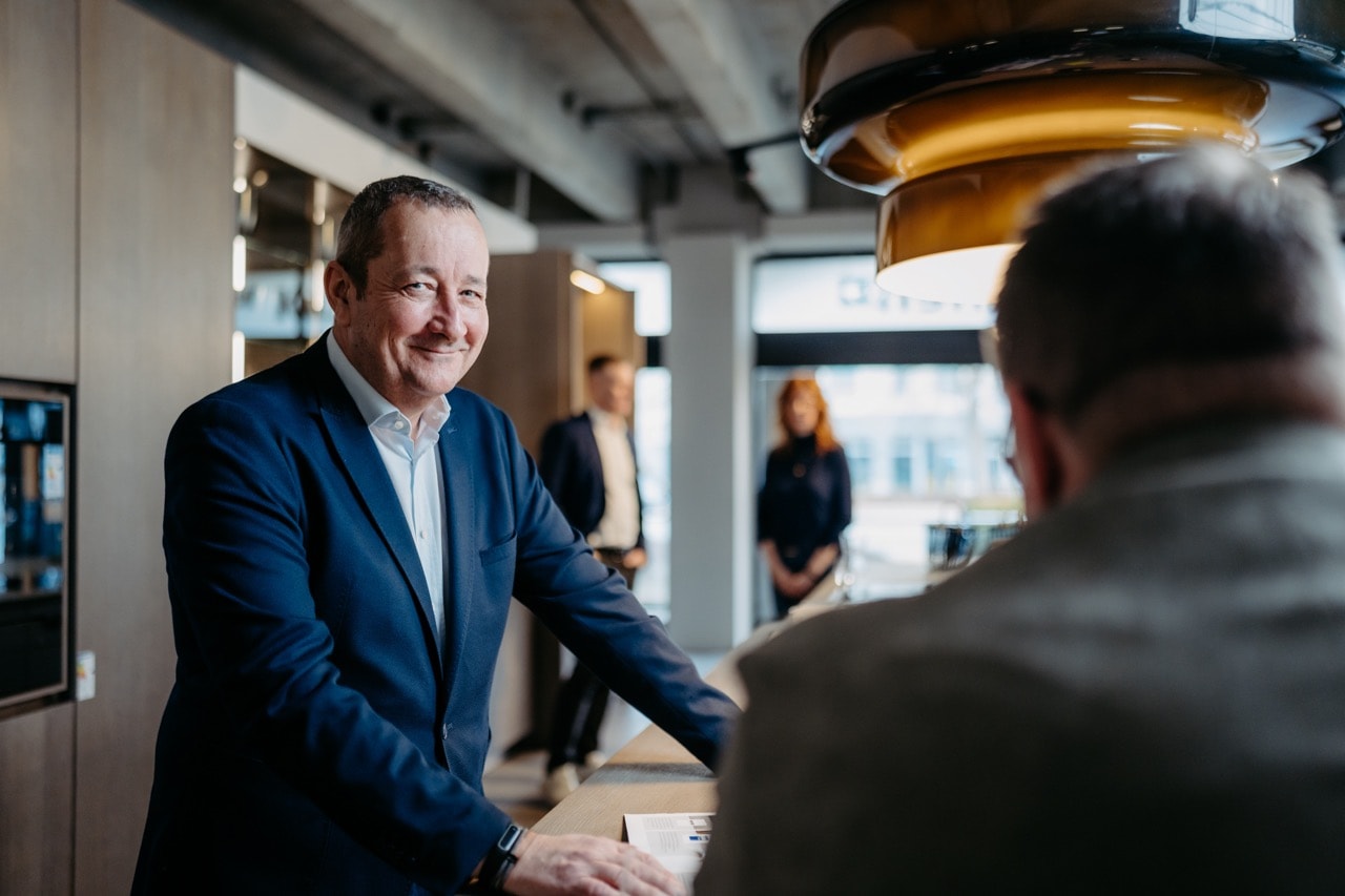 Stefan Tiemann begrüßt jemanden herzlich und lacht