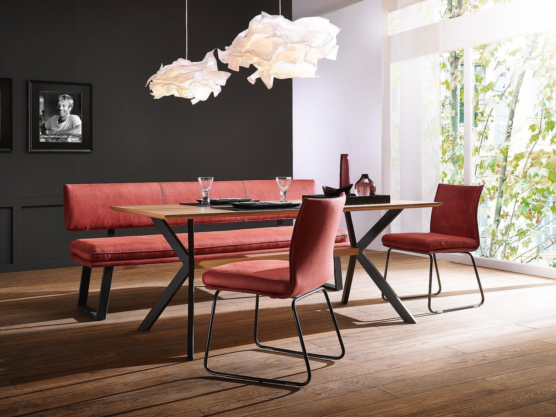 Schösswender Memphis Bankgruppe in Koralle mit Esstisch und Stühlen vor dunkler Wand